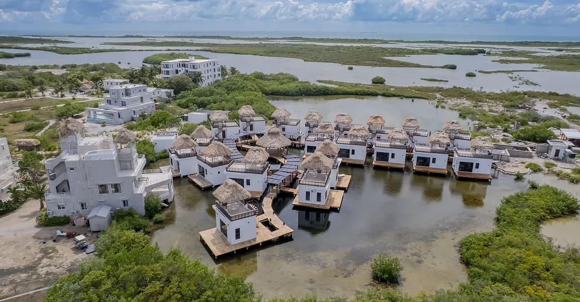 Thatched overwater homes on a boardwalk above the Ambergris Caye lagoon